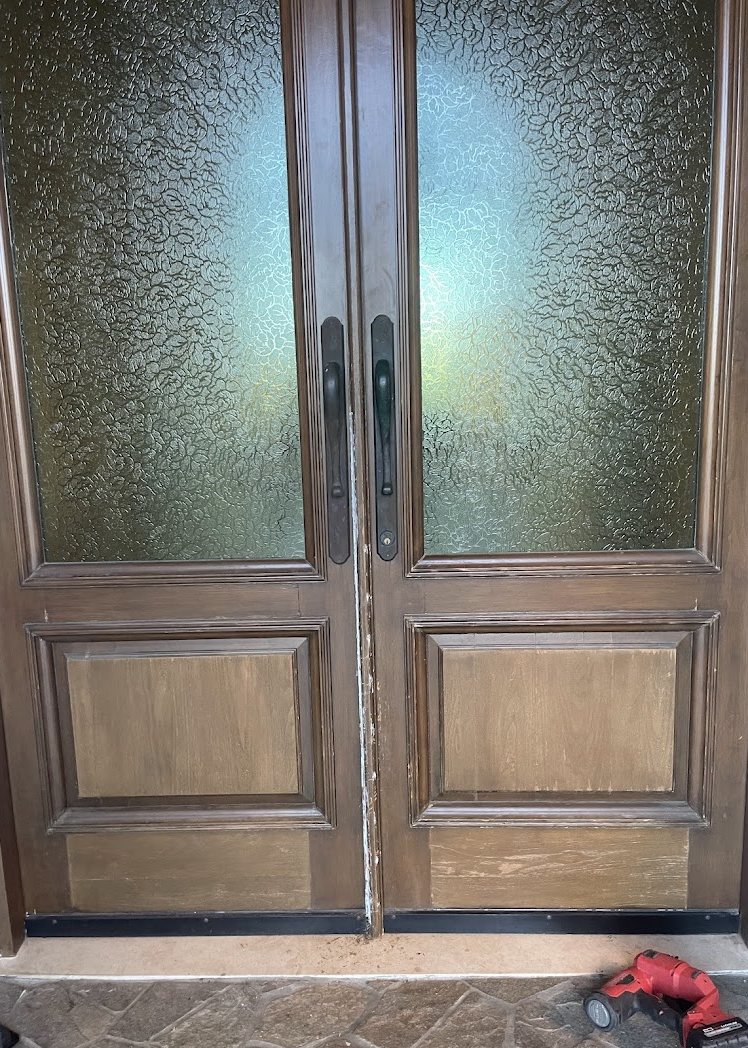 Entry doors with a patchy, sun-bleached finish and worn lower panels