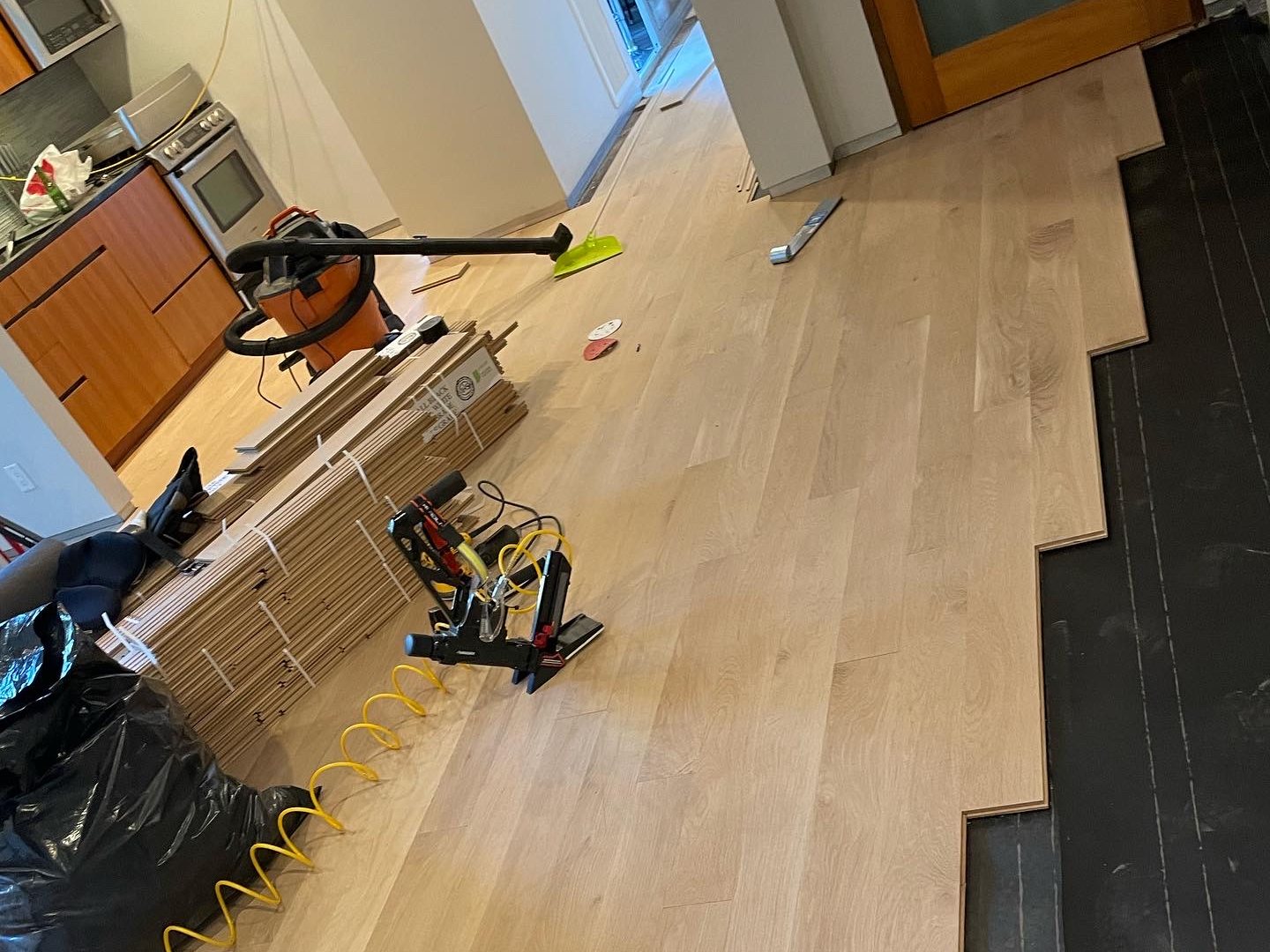 New hardwood planks being laid alongside the old dark floor being replaced