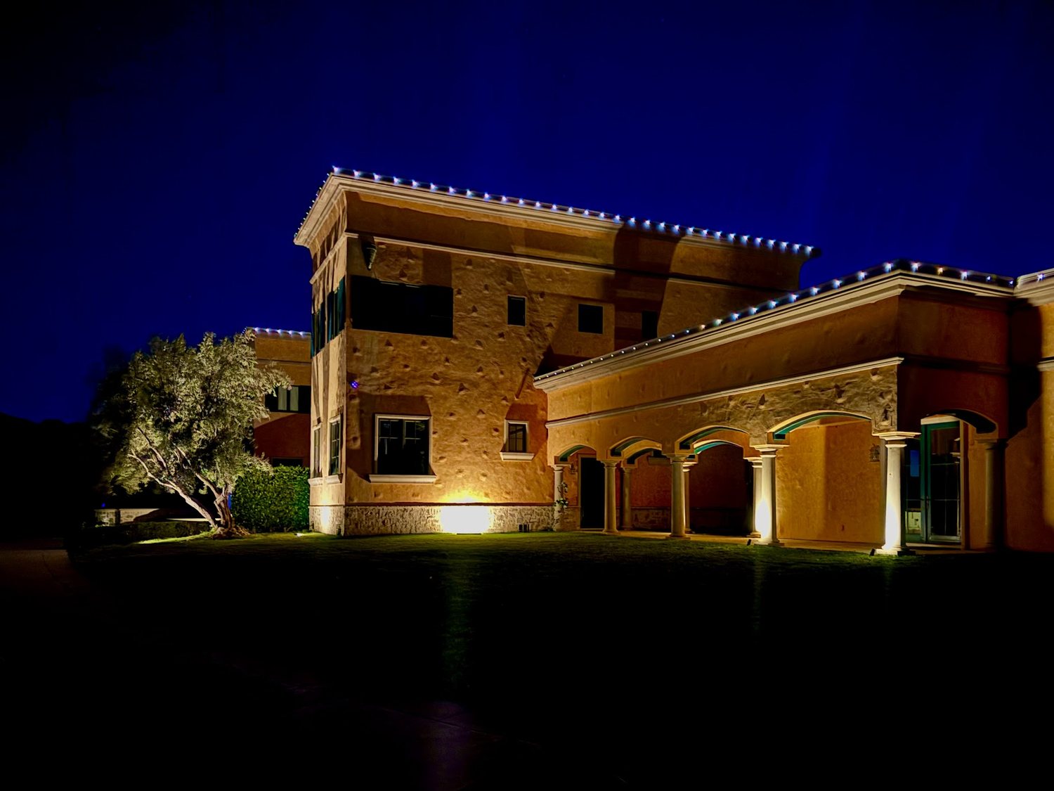 Estate exterior lit at dusk by landscape and architectural lighting
