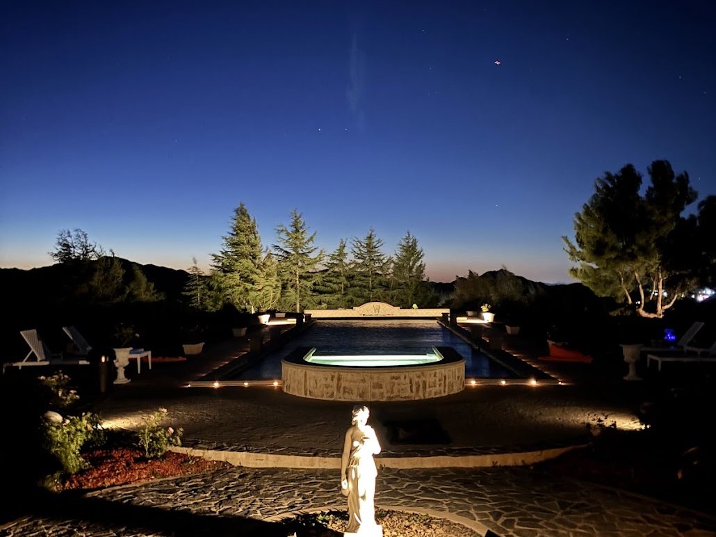 Fountain and statue lit at dusk with path lighting