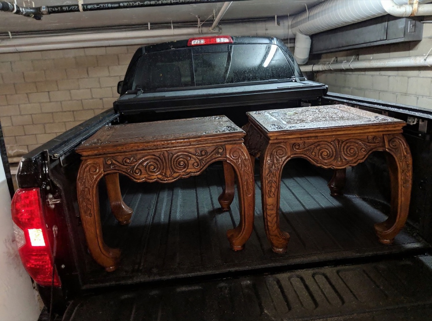 Two carved coffee tables loaded in a truck bed in the rain